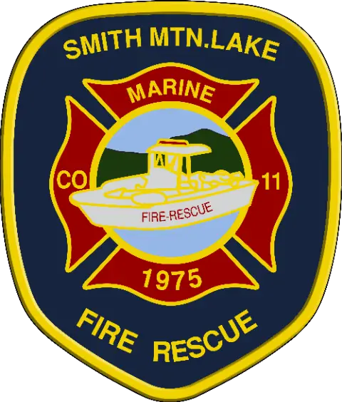 A badge for the Smith Mountain Lake Fire Rescue Marine Company 11 established in 1975. The badge features a white rescue boat against a backdrop of blue water and green hills, surrounded by red and outlined with a yellow border.